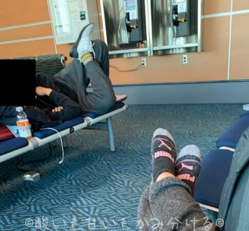 バンクーバー空港内で仮眠をとる人と足を延ばして座る人