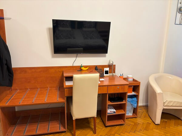 Paprika Apartment Studio内ベッド向かいのテレビ・机・一人掛けソファー