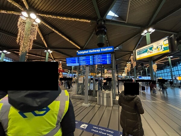 スキポール空港駅の電光掲示板と左下のNS鉄道の係員さん