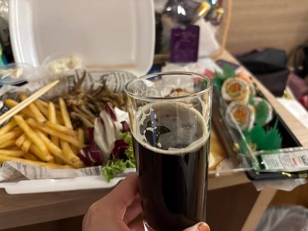 ホテルの部屋でディナー。カルロヴァチュコ・ツルノ（黒ビール）と、サーモンアボカド巻き、小魚のフライ、フライドポテト
