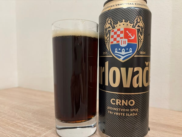 ホテルの部屋で撮影した、Karlovačko Crno（カルロヴァチュコ・ツルノ）の缶とグラスに注がれた濃厚な黒ビール