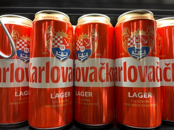 クロアチアのスーパーの棚にずらりと並んだ、赤いラベルの定番ラガービールKarlovačko（カルロヴァチュコ）の缶