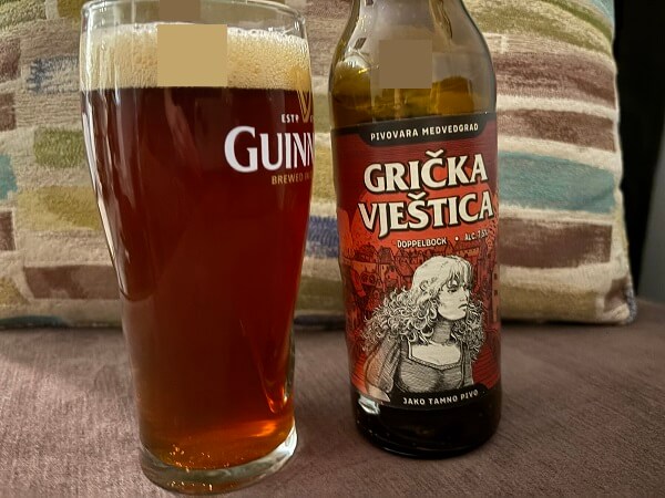 自宅で撮影した、魔女のイラストが描かれたGrička vješticaのボトルと、グラスに注がれたルビーレッド色のビール