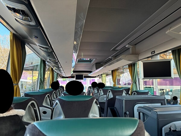 大型長距離バスの車内。グリーンとグレーのシートが並ぶ清潔な車内の様子。