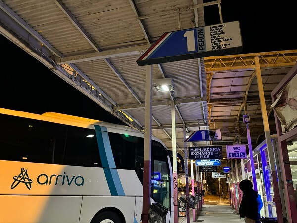 夜のスプリトバスターミナルの1番乗り場(PERÓN 1)。頭上に設置された行き先案内看板と停車中のarrivaバス。