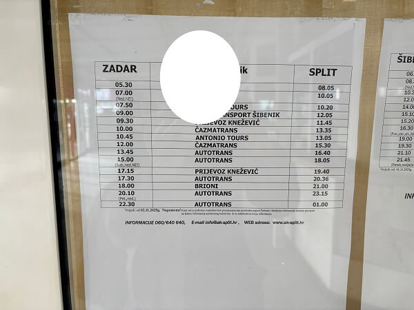 スプリトバスターミナルに掲示された、ザダルからスプリト行きのバス時刻表。紙には「ZADAR」発と「SPLIT」着の時刻、バス会社名(ANTONIO TOURS、BRIONIなど)が並んでいる。中央上部に白い丸の隠しがある。